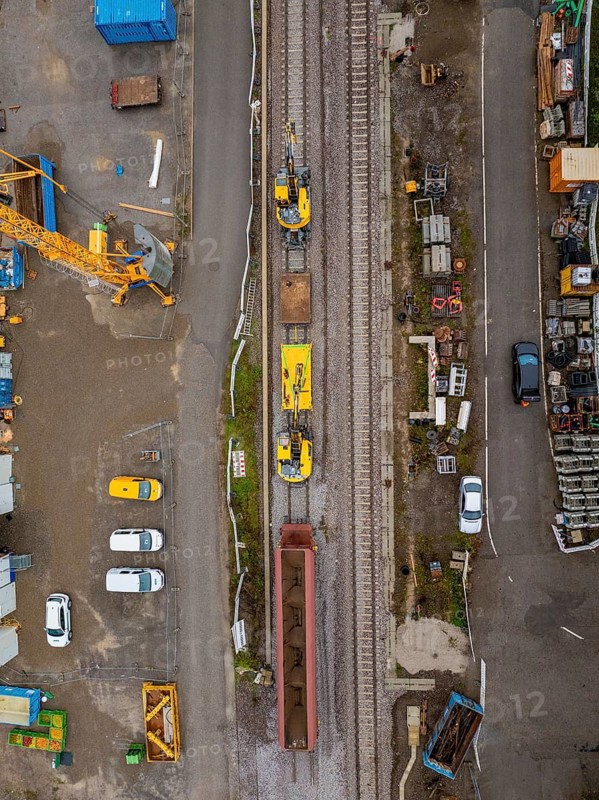 Aerial view of a construction site with a yellow train on rails and a road next to it, tamping machine, Hermann Hessebahn, Althengstett, Black Forest, Germany
