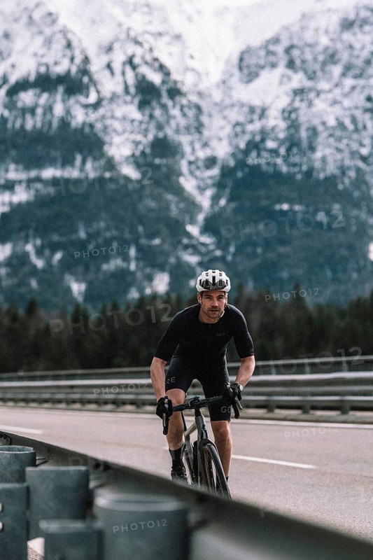 Road bike rider in spring between Lechtal and Tannheimer Tal in front of picturesque scenery of the Alps, Tyrol, Austria