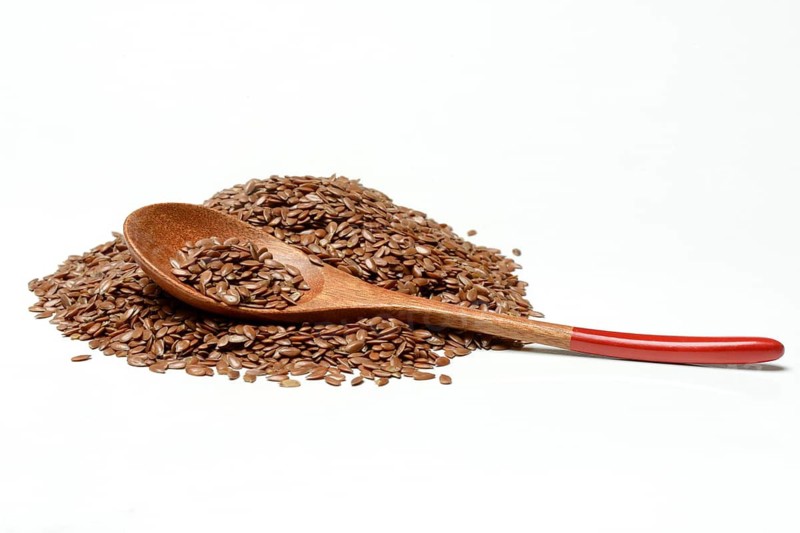 Linseed with wooden spoon, seeds of the common flax (Linum usitatissimum)
