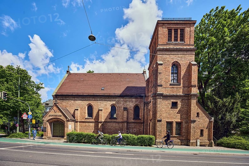 St. Willibrord church, roadway, lanes, cyclists and pedestrians as secondary motifs, blue sky, cumulus clouds, Blumenstraße street, Munich, state capital, district-free city, Bavaria, Germany