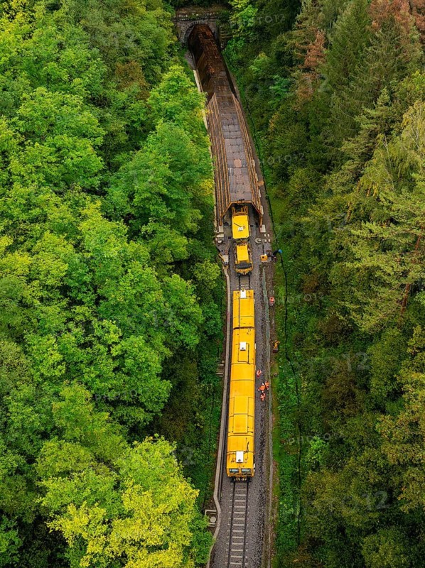 Yellow train travelling through a tunnel in a forest, bird's eye view, tamping machine, Hermann Hessebahn, Althengstett, Black Forest, Germany