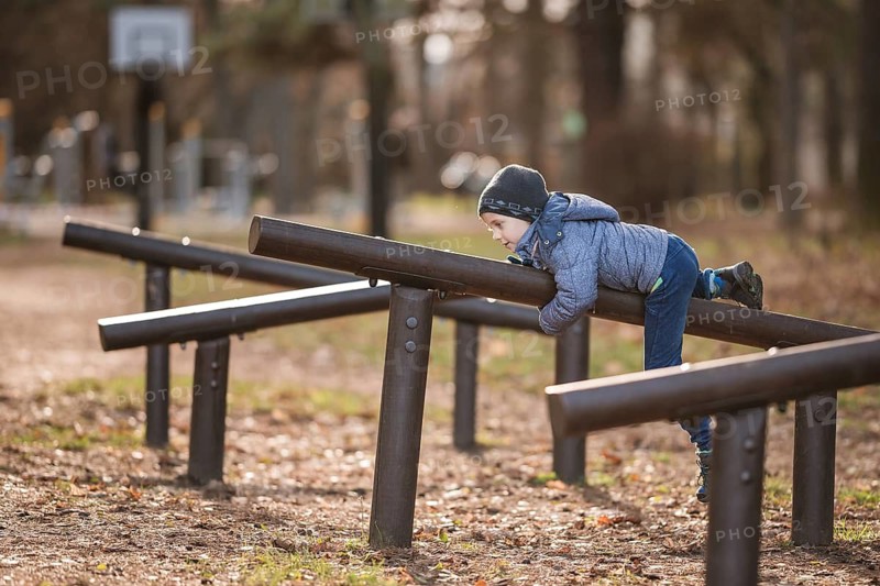 Six years old boy exercises at the obstacle course in the park