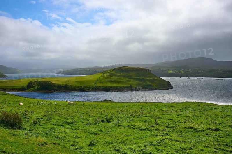Green island with blue sky and clouds over a calm sea, Isle of Skye, Scotland, United Kingdom, United Kingdom