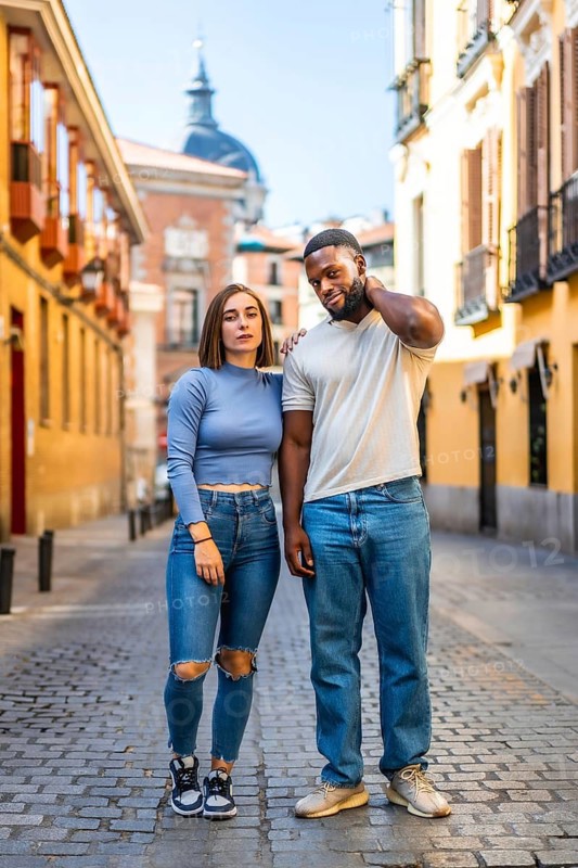 Vertical Portrait of multi-ethnic couple in denim clothes standing in the city