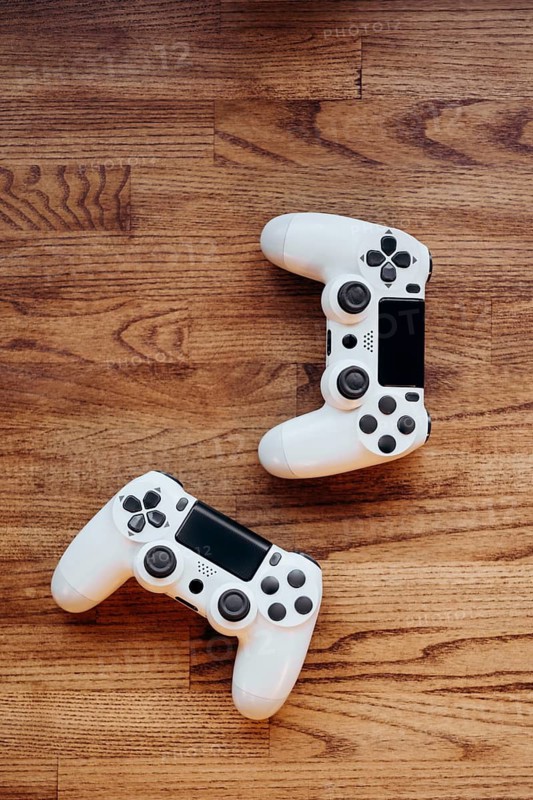 Two white gaming controllers lay on a wooden surface, highlighting sleek design and modern technology, perfect for interactive gaming experiences and entertainment