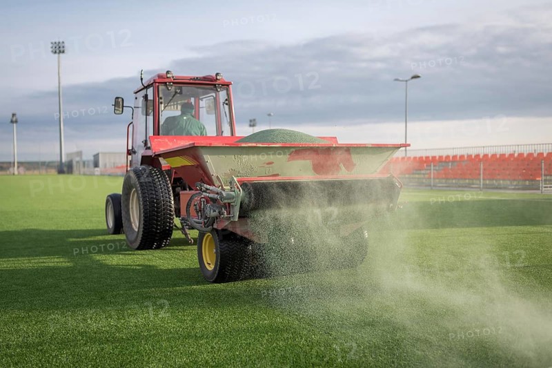 Pouring infill granules in to a football pitch with artificial grass in Lubin, Poland