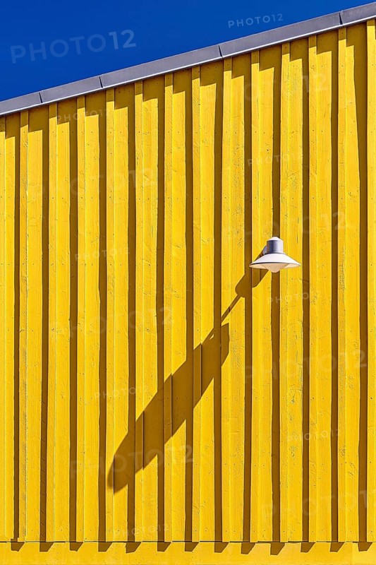 Wooden façade of a yellow beach hut, lamp casting long shadows, blue sky, Oleron Island, Île d'Oléron, Charente Maritime, Poitou-Charentes, France
