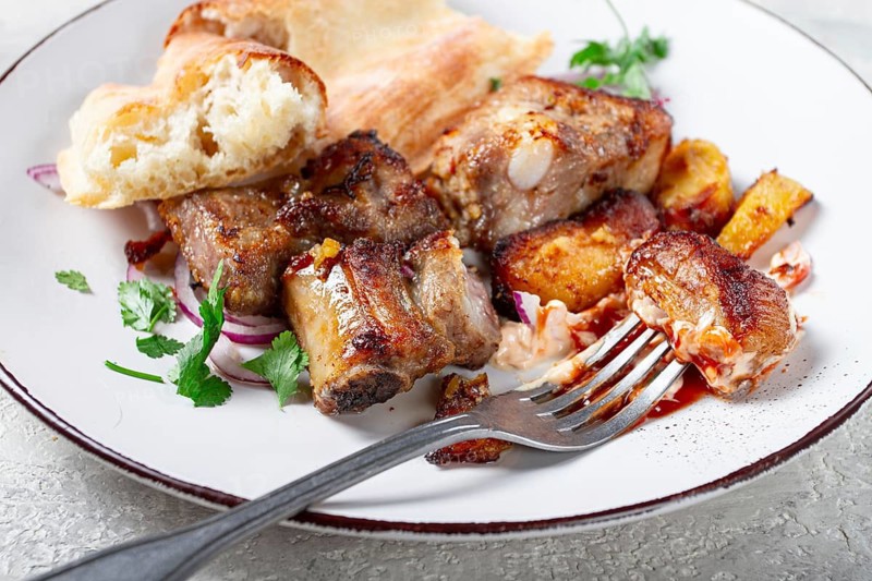 A plate with leftover pork kebab, with bread, on a white plate, close-up, there are no people