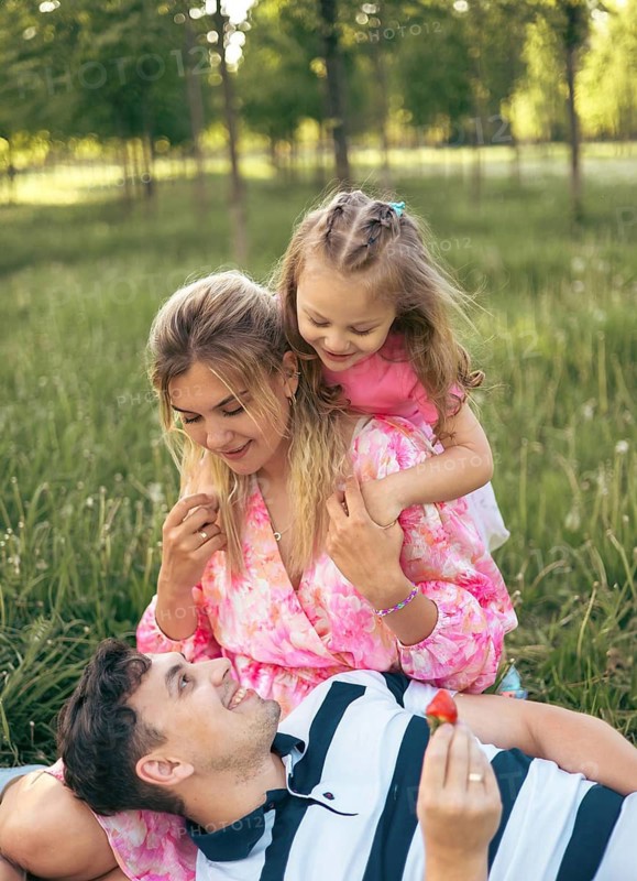 Young parents with their little daughter on a picnic in the park in summer. Family time together