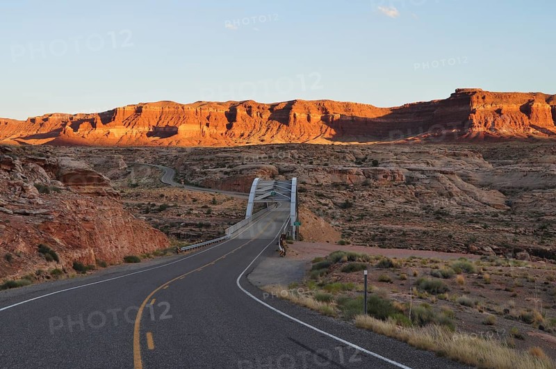A bridge crosses a road through a rocky landscape at sunset, Lake Powell, Arizona, USA