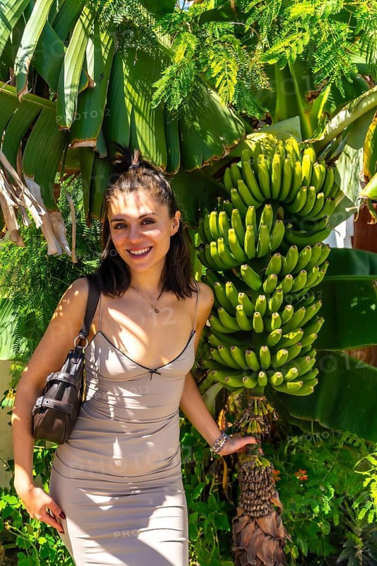 Young woman posing next to a banana tree in ojos de garza village, gran canaria, canary islands, spain