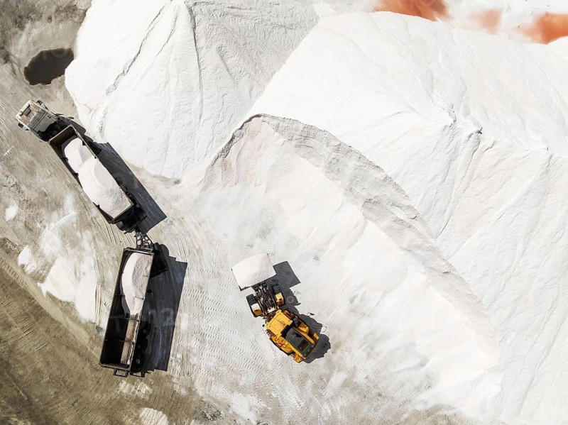 Lorry and excavator at the salt heaps of the Walvis Bay Salt works. Aerial view. Drone shot. Walvis Bay, Namibia