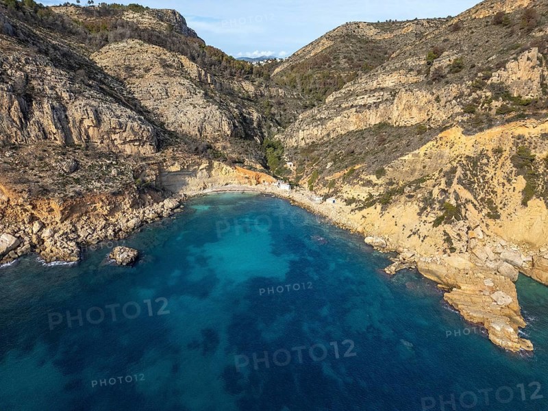 A breathtaking view of the Costa Blanca coastline, where the crystal-clear Mediterranean Sea gently meets the rugged cliffs, capturing the essence of nature's beauty