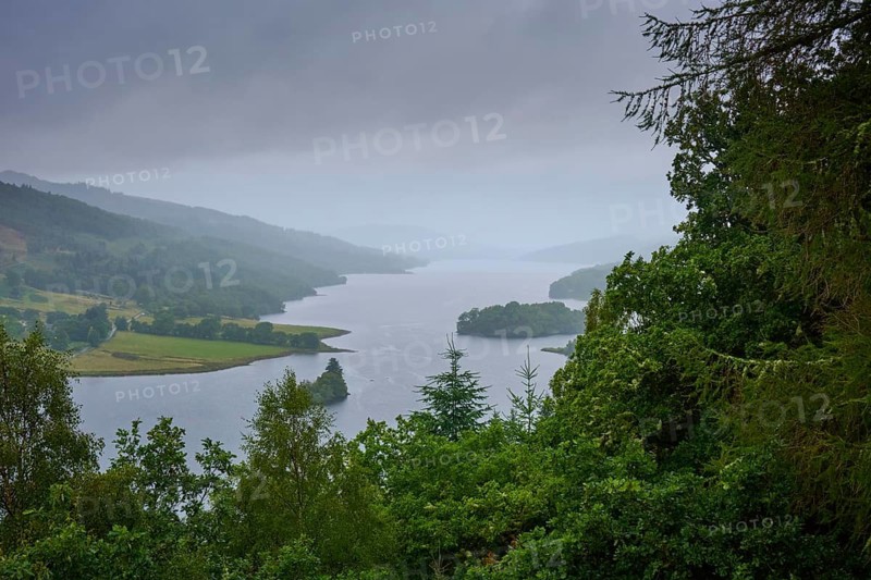 Calm lake under cloudy sky surrounded by green hills and thick vegetation, Queens View, Fincastle, Pitlochry, Scotland, United Kingdom, Great Britain