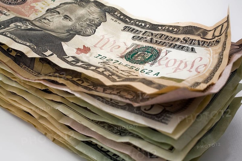 Close-up of stack of creased and wrinkled US paper currency bank notes on white background, Studio Composition, Quebec, Canada