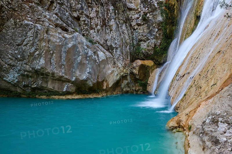 Close-up of a waterfall flowing into a turquoise pool surrounded by rocks, waterfalls, ponds, Polylimnio, Peloponnese, Greece