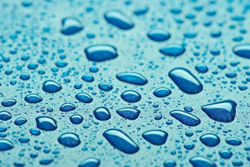 A striking close up image showcasing glistening blue water droplets on a textured surface. The droplets vary in size, highlighting the natural beauty and serenity of water