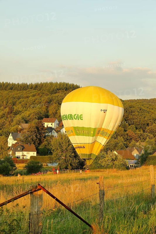 Hot air balloon with advertising Siegener Versorgungsbetriebe flying over a wooded area, Wilnsdorf, North Rhine-Westphalia, Germany