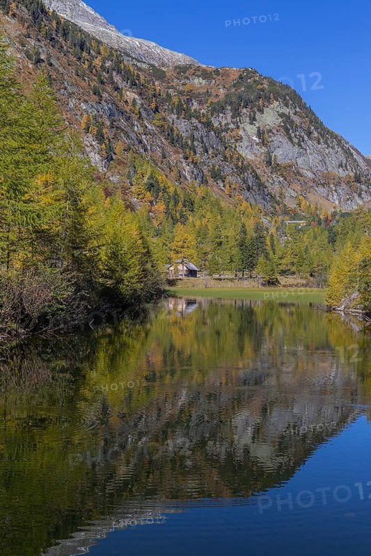 Little pond of the Malta river with a mountain forest in fall foliage on a bright sunny morning. Seen from the Malta Hochalm road. Carithia, Austria