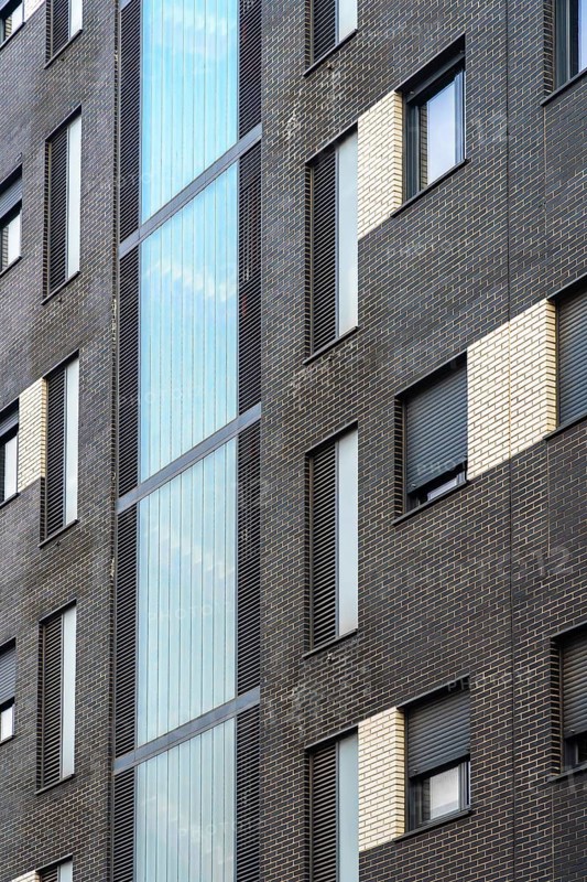 Striking image of a modern urban building featuring a blend of dark brick and reflective glass panels, emphasizing contemporary architectural styles