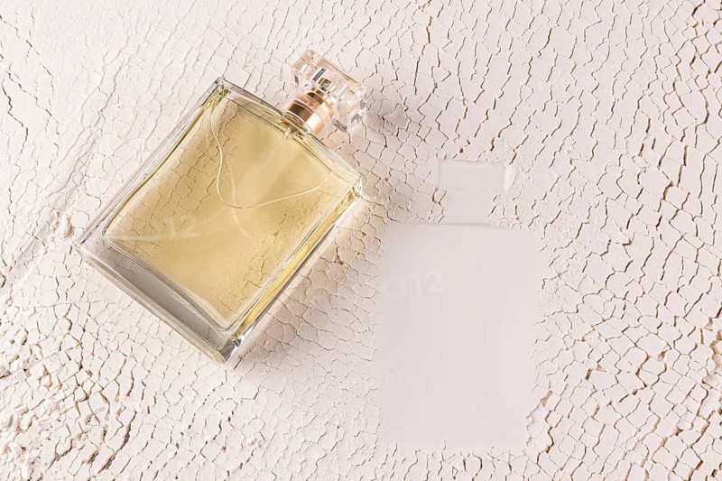 A stylish male perfume bottle lies on a textured, sand white surface, capturing an essence of elegance and sophistication Perfect for beauty and lifestyle themes