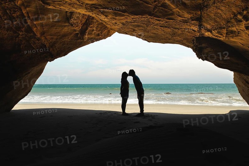 A couple shares a romantic moment in Mancora, Peru, silhouetted against the backdrop of a serene beach and ocean. The perfect setting for love and tranquility