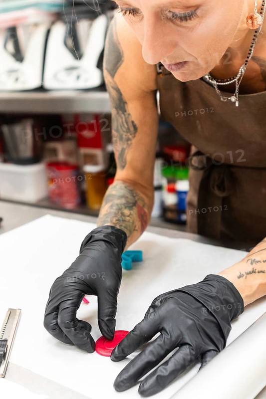 Skilled artisan in an Italian bakery, wearing black gloves and an apron, crafting intricate edible decorations Precision and passion for traditional baking are evident