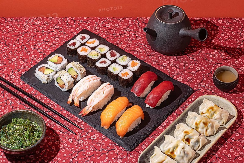 Top-down view of an elegant sushi dinner, presented on a floral red tablecloth with dramatic shadows