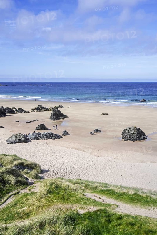 Tourists walking on sandy beach with rocks near Durness, Sutherland, Scottish Highlands, Scotland, UK