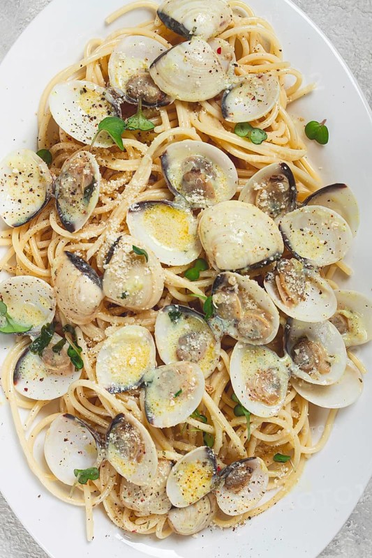 Spaghetti with vongole clams, in cream sauce, carbonara, on a white plate, homemade, top view, no people