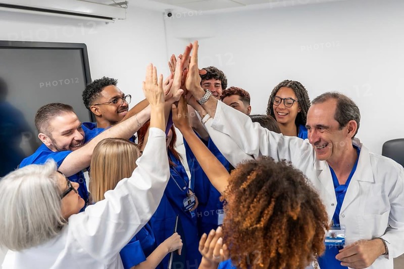 Diverse medical professionals and students uniting hands in a meeting room, symbolizing teamwork, collaboration, and shared success in healthcare training and professional development