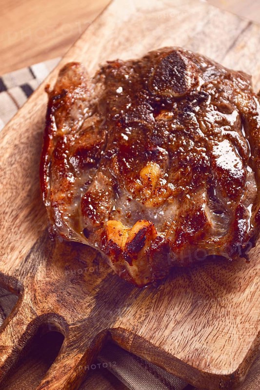 Fried steak, veal neck on the bone, cooking meat, on a wooden board, top view, no people