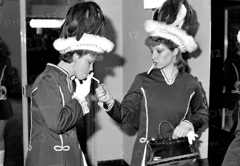 Essen, DEU, 19.02.1984 - Two spark girls take a cigarette break during a men's meeting of the Borbecker Böse Buben Carnival Association, Essen, Germany
