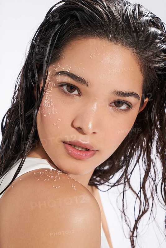 Studio portrait of a young female model with wet hair and salt crystals on her face and shoulder, looking at the camera
