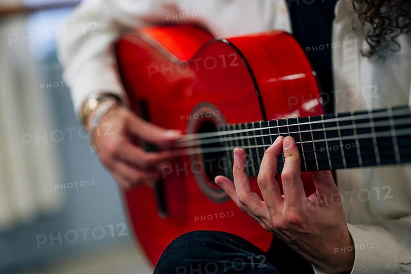 Anonymous Latin man playing red bass guitar in studio