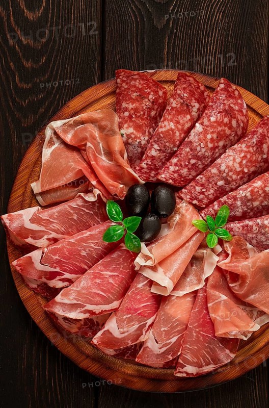 Assortment, sliced meat appetizer, prosciutto, salami and ham, with olives, breakfast, top view, close-up, no people