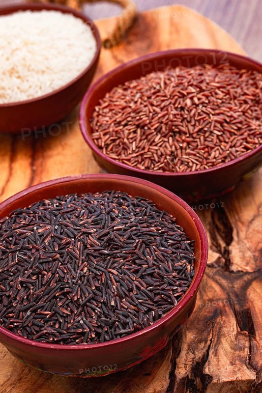 Set of red and black and white rice, in a bowl, on a wooden surface, rustic style, top view