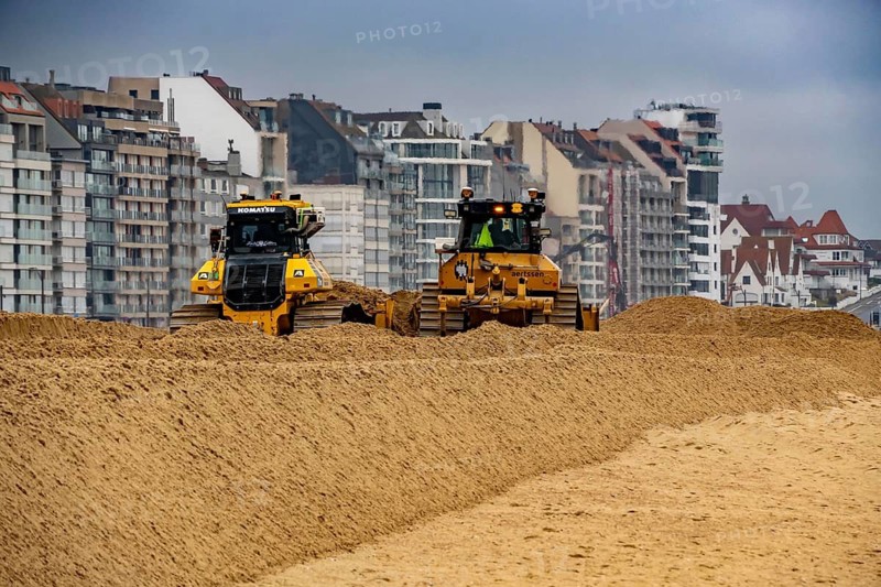 Bulldozers when distributing sand on the beach in the town of Knokke-Heist, part of coastal protection and beach maintenance, due to floods, erosion and sea level rise, the sand on the beach is repeatedly washed into the sea, in winter the sand from the seabed is washed back onto the beach with suction vessels, the excavators and levelers then distribute the sand back on the beach to eliminate the difference in height so as to bathe To make the beach usable again for the next season