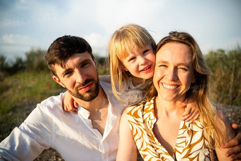 A joyful family of three enjoys a sunny day at a beach in Italy. The scene captures the happiness and togetherness of a memorable family vacation by the sea