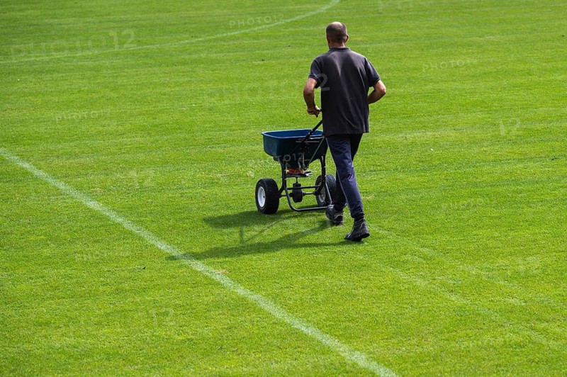 Groundsman spreads artificial fertilizer for grass on a football pitch in Lubin, Poland
