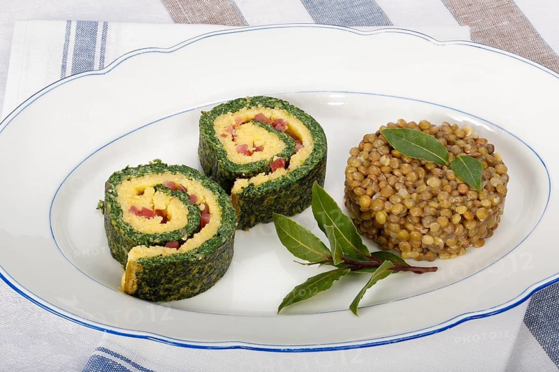 Southern German cuisine, polenta spinach roulade with alblentils served on serving platter, bay leaves, lentil vegetables, smoked meat, bacon cubes, healthy, food photography, studio, Germany