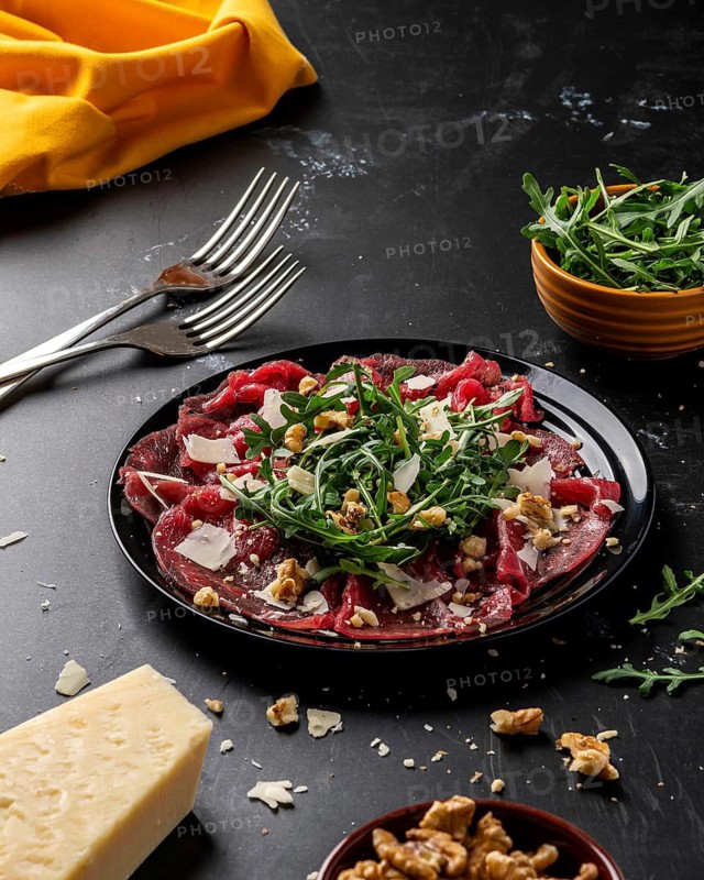Elegant carpaccio on a dark plate, garnished with arugula and shaved cheese, presented on a sophisticated dark table setting. A perfect dish combining freshness and luxury