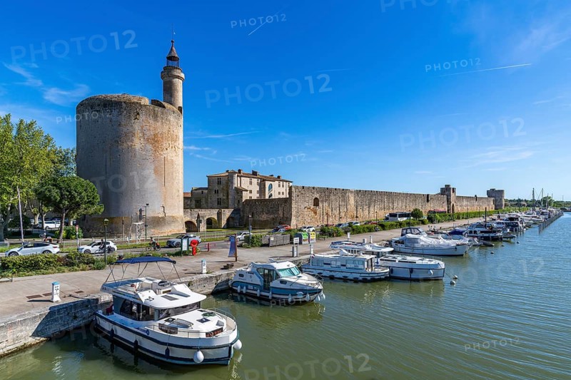 Yachts and motorboats are moored in the harbor on the Rhone-Sete Canal in front of the Tour de Constance defensive defence tower and the medieval city wall, Aigues-Mortes, Camargue, Provence, France