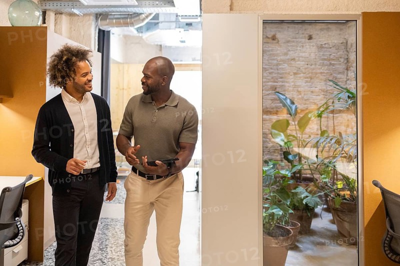 Two men engaged in a dynamic discussion at a coworking space in Barcelona. The environment showcases modern design elements and a collaborative atmosphere ideal for creativity