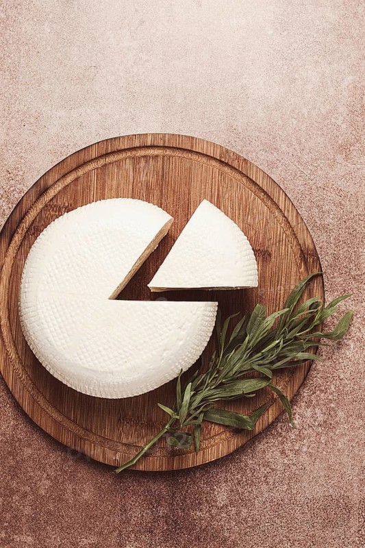 Head of Georgian cheese, Imereti variety, top view, on a cutting board