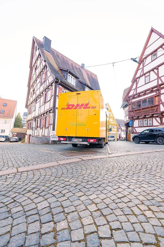 DHL delivery van on cobbled street in front of traditional half-timbered houses, urban environment, Sindelfingen, Böblingen district, Germany
