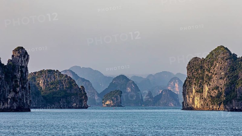 Mighty rocky islands in the soft light of dusk over a calm sea, The landscape and islands of Halong Bay in Vietnam