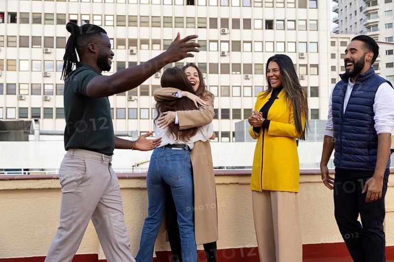 A diverse group of friends gathers on a rooftop, joyfully celebrating their friendship Laughter and hugs are shared, highlighting the warmth and connection among them