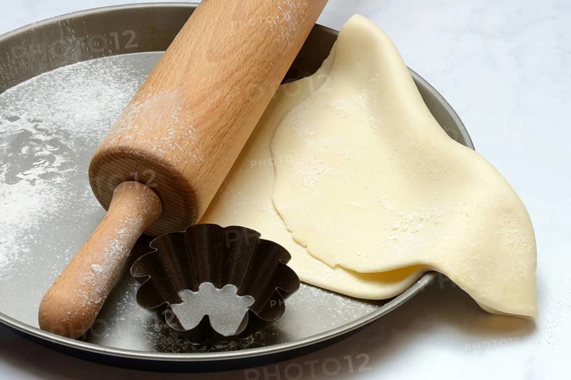 Rolled dough on baking tray with rolling pin