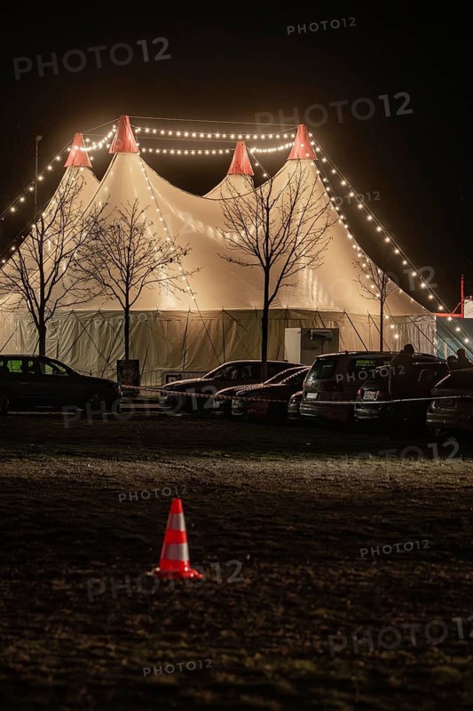 Illuminated circus tent at night, surrounded by parked cars and fairy lights, Böblingen, Germany